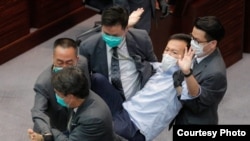Los guardias de seguridad arrastran al legislador pro democracia Ray Chan durante una reunión legislativa el 8 de mayo de 2020 en Hong Kong. 