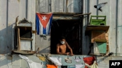 Un hombre se asoma a un balcón, en La Habana, con una máscara para protegerse del coronavirus. (Foto: Yamil Lage/AFP).
