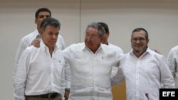  El presidente de Colombia, Juan Manuel Santos, el máximo líder de las FARC, Rodrigo Londoño, alias "Timochenko", y el presidente de Cuba, Raúl Castro, participan en el acto para presentar un acuerdo en los diálogos de paz en La Habana (Cuba).