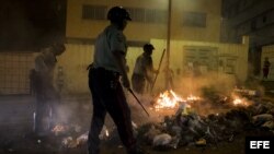 Efectivos policiales tratan de limpiar una de las calles bloqueadas
