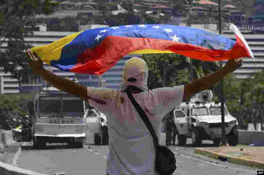 Un partidario del presidente interino de Venezuela, Juan Guaido, muestra una bandera nacional frente a las tanquetas del ejército. 