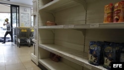 Un hombre ingresa a un supermercado con estanterías desabastecidas en Caracas.