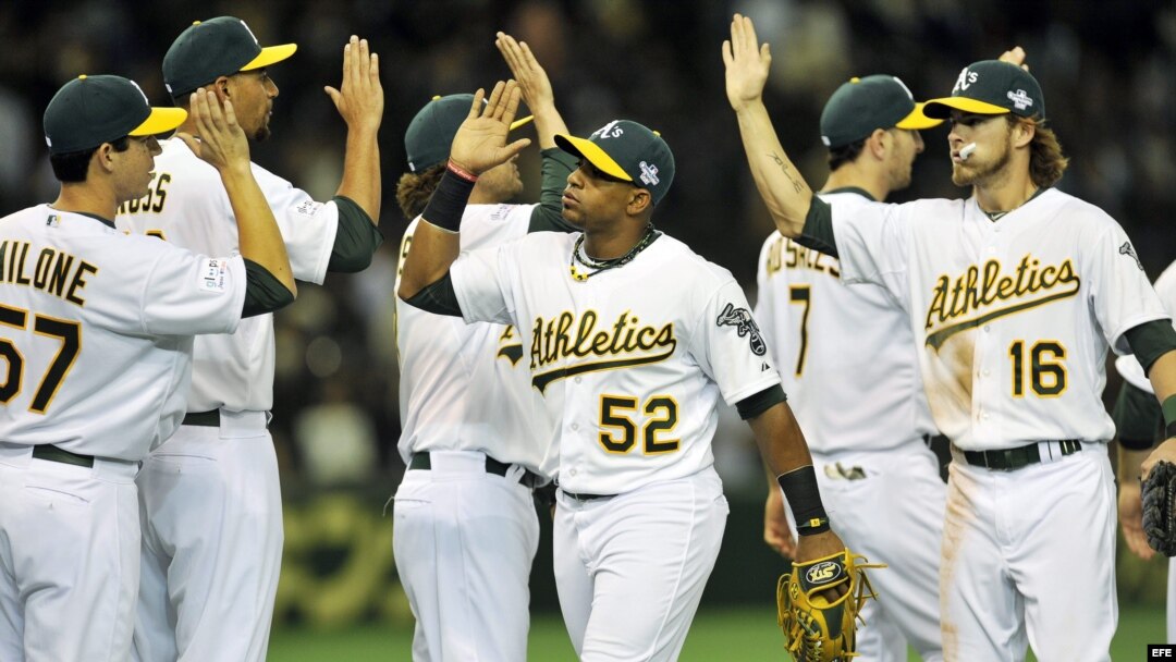 El jugador de los Atléticos de Oackland Yoenis Cespedes (centro) y Josh Reddicks (dcha)
