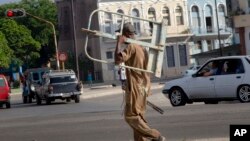 Un hombre carga un utensilio de trabajo en La Habana el 27 de junio de 2019. (AP).