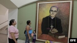 Salvadoreñas observan una pintura del arzobispo de San Salvador Óscar Arnulfo Romero, en la capital del país. 