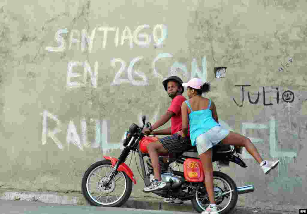 A woman gets on a motorcycle in the city of Santiago de Cuba.