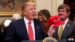 El presidente Donald Trump sostiene su gorra de campaña en el salón Roosvelt de la Casa Blanca.