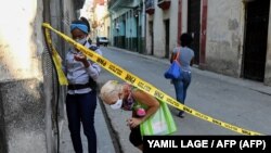 Una agente de la policía controla el acceso a un barrio de La Habana en cuarentena por COVID-19. (YAMIL LAGE / AFP)