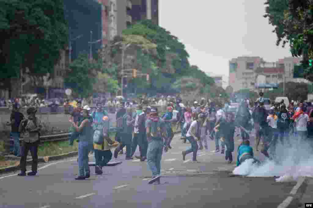 Manifestantes protestan en medio de gases lacrimógenos lanzados por miembros de la Policía Nacional Bolivariana (PNB) hoy, 18 de mayo de 2016, en la ciudad de Caracas (Venezuela).