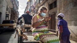 Una mujer que usa una máscara para frenar la propagación del nuevo coronavirus mira su teléfono móvil mientras viaja triciclo en La Habana. (AP Foto/Ramón Espinosa)