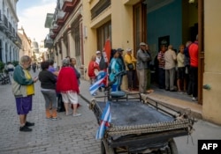 Cubanos hacen cola para comprar alimentos en una bodega en La Habana.