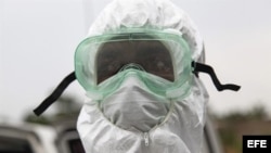 Un enfermero liberiano trabaja en la retirada y entierro de una víctima del ébola en la comunidad de Virginia, a las afueras de Monrovia. Liberia afronta hoy el estado de emergencia declarado anoche por su presidenta.