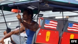 Un bicitaxista cubano exhibe la bandera estadounidense.