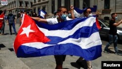 Un hombre sostiene una bandera cubana durante una manifestación frente al parlamento español, en Madrid, en apoyo a las protestas contra el gobierno en Cuba. (REUTERS/Javier Barbancho)