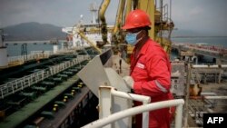Trabajador de PDVSA observa un carguero de petróleo con bandera iraní en Puerto Cabello, una de las refinerías de la petrolera estatal venezolana.