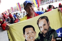 Un hombre muestra una bandera venezolana con el rostro de Hugo Chávez junto al de Fidel Castro, en el Paseo de Los Próceres, en Caracas, antes de que sus restos mortales sean trasladados al Museo Militar de la ciudad