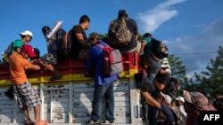 Migrantes hondureños que forman parte de la caravana que se dirige a EEUU se suben a un camión en Oaxaca, México.