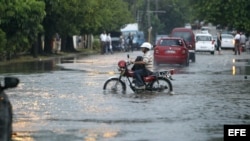 Un hombre conduce una motocicleta por una calle inundada en La Habana. (EFE/Archivo)