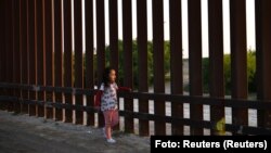 Niña centroaméricana camina junto a la valla México-EEUU
