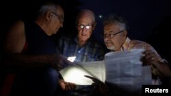 Cubanos leen proyecto de reforma constitucional bajo un apagón.