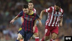 El delantero argentino del FC Barcelona, Leo Messi (i), lucha el balón junto al turco Arda Turan, del Atlético de Madrid 