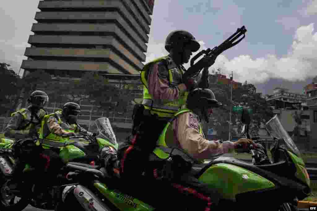 Miembros de la Policía Nacional Bolivariana (PNB) patrullan en motocicletas fuertemente armados frente a la manifestación.