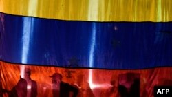 La silueta de tres activistas en una bandera de Venezuela.