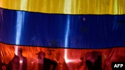 La silueta de tres activistas en una bandera de Venezuela.