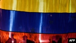 La silueta de tres activistas en una bandera de Venezuela.