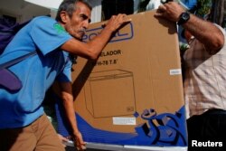 El chofer Héctor Castro carga un refrigerador comprado el lunes en una de las tiendas en La Habana (Foto: Alexandre Meneghini/Reuters).