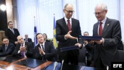 El primer ministro de Ucrania, Arseniy Yatsenyuk (c), intercambia documentos con el presidente del Consejo Europeo, Herman Van Rompuy (d) durante el encuentro con los jefes de Estado y de Gobierno de la Unión Europea (UE), en Bruselas (Bélgica).