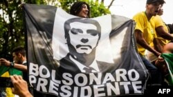 Simpatizantes de Jair Bolsonaro despliegan una tela con su imagen poco antes de la primera vuelta electoral en Brasil, que el candidato conservador ganó con más del 46% de los votos.