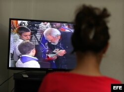 Una mujer observa el Noticiero Nacional de la Televisión cubana que muestra imágenes de Fidel Castro ejerciendo su derecho al voto.