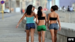 Tres mujeres caminan por el malecón. 