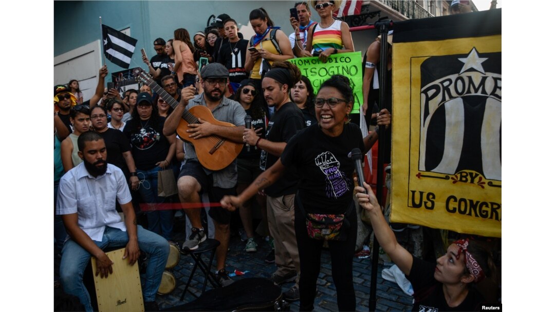 Miembros del grupo de teatro Papel Machete actúan durante la protesta de este lunes en San Juan.