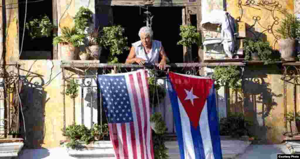 Una señora señaliza su balcón en La Habana con la bandera cubana y la que se ha puesto de moda, &#39;la de las barras y las estrellas.