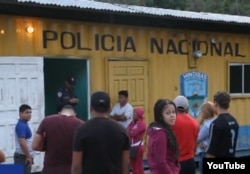 Un grupo de cubanos en tránsito, incluidos niños, espera ante un puesto de la policía hondureña