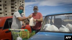 Dos hombres acomodan la mercancía adquirida en una de las tiendas en dólares abiertas la semana pasada en Cuba. (Adalberto Roque / AFP)