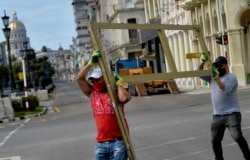 Trabajadores de un hotel próximo al Paseo del Prado cuando se preparaban para proteger el fin de semana las ventanas de la instalación (Yamil Lage/AFP).