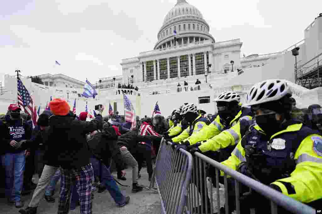 Partidarios de Trump intentan romper una barrera policial en el Capitolio, en Washington. (AP Photo/Julio Cortez)
