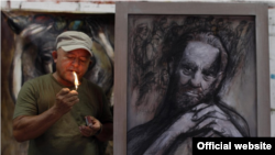 Nelson Domínguez fuma junto a una de sus obras inspiradas en Fidel Castro.