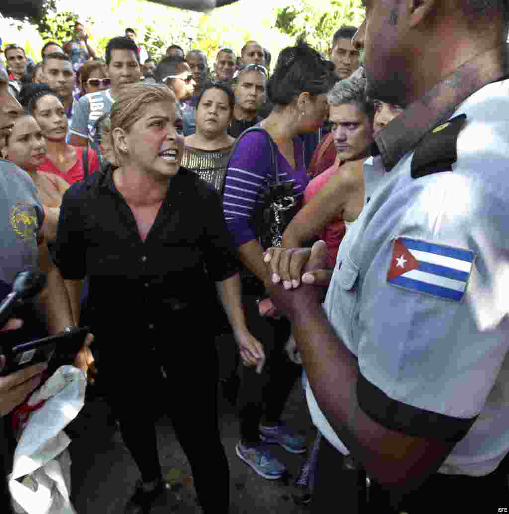Una mujer discute con un uniformado mientras un grupo de cubanos protesta frente a la embajada de Ecuador en Cuba. 