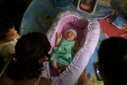Peyton, de dos días de edad, yace en una canasta mientras su familia la cuida en su departamento