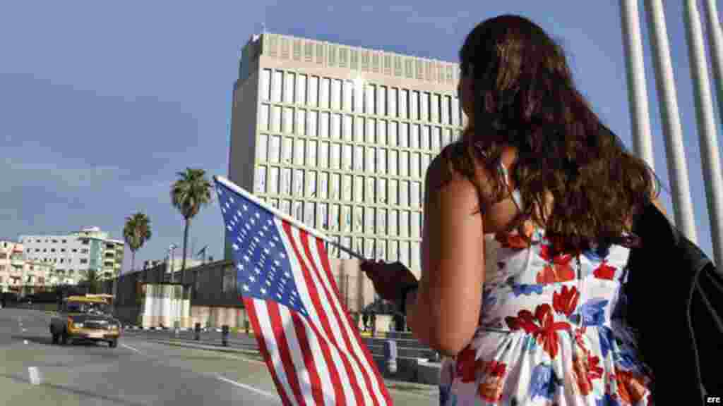 Una mujer camina con una bandera de EE.UU. frente a la embajada de ese país en La Habana