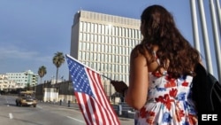 Una mujer camina con una bandera de EE.UU. frente a la embajada de ese país en La Habana