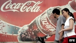 Foto de archivo del 14 de junio de 2005 que muestra a una pareja caminando frente a una publicidad de Coca-Cola en PeKín, China.