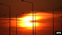 04.- El sol se pone detrás de unos postes de iluminación en el malecón habanero. 