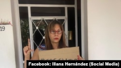 La periodista independiente Iliana Hernández en La Habana con un cartel que dice SOS Cuba.