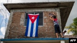 Una mujer adorna su casa con una bandera cubana.