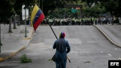 Un manifestante camina frente a efectivos de la Policía Nacional Bolivariana (PNB) el 7 de junio de 2017, en Caracas.